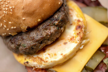 Bun with grilled meat, scrambled eggs and cheese. Cheeseburger, Close Up shot. Junk hearty food. Horizontal format.