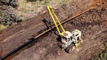 Pipeline laying. Gas and oil industry. A tractor pipelayer installs a pipe in a trench. 