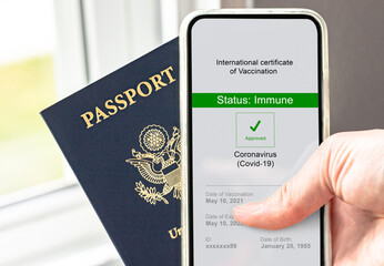 Hand holding mobile phone with covid vaccinated certification approved on screen and passport, digital data and identification of passenger require for worldwide travel in new normal. Immunity record.