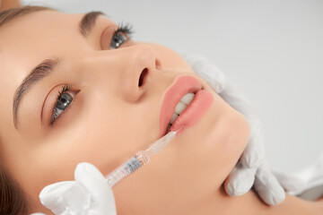 Close up portrait of attractive young woman on procedure injection in lip with special preparation....