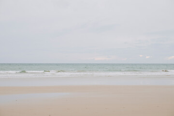 Fototapeta na wymiar Playa azul y cielo nublado