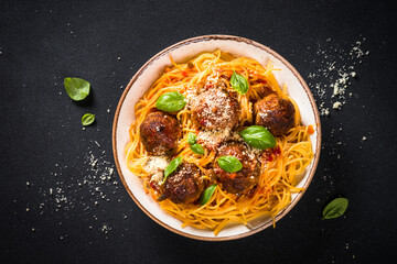 Pasta with Meatballs in tomato sauce, basil and parmesan on dark stone table. Top view with copy space.