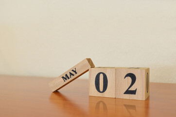 May 2, Date design with calendar cube on wooden table and white background.