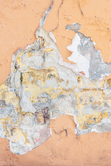 Orange Wall with cracked paint. Background for creative projects. Cracked wall with old layers of paint in abandoned house. Abstract orange vertical Empty Wallpaper..