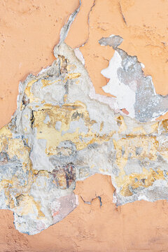 Orange Wall with cracked paint. Background for creative projects. Cracked wall with old layers of paint in abandoned house. Abstract orange vertical Empty Wallpaper..