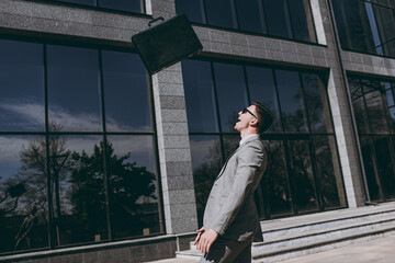 Side view young overjoyed smiling employee business man 20s in grey suit stand near office glass...