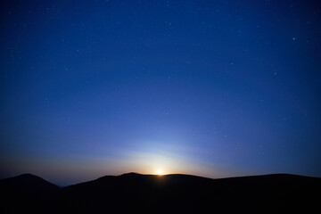 Blue dark night sky with many stars. Moon rising, night background