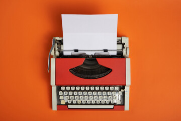 Top view of red vintage typewriter with white blank paper sheet - Powered by Adobe
