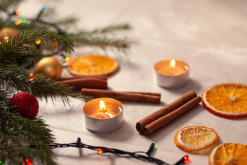 Obraz premium Christmas decorations on the table. Burning candles near the christmas tree branches, cinnamon and dried orange