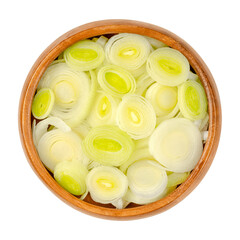 Leek slices, in a wooden bowl. Chopped leaf sheaths and cross sections of Allium ampeloprasum, a crunchy and firm vegetable with mild and onion-like taste. Close-up from above, over white, food photo.