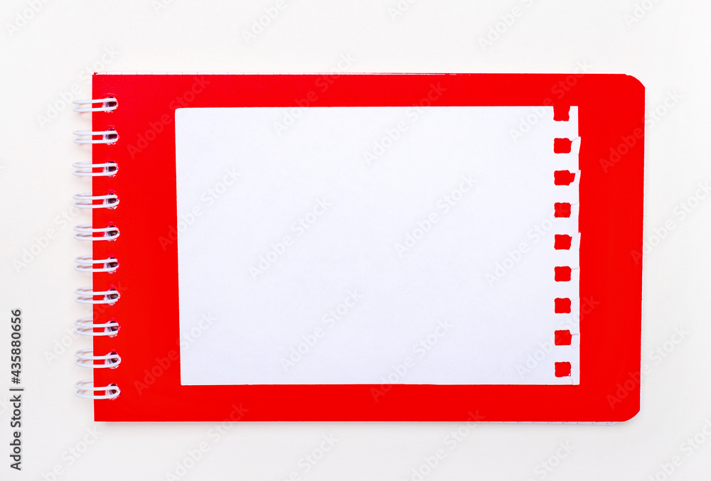 Aufkleber on a white background is a bright red notebook in a spiral. above is a white blank sheet of paper wi