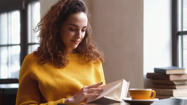 A lovely woman is reading a book sitting in the cafe inside
