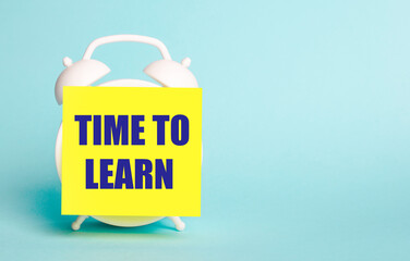 On a blue background - a white alarm clock with a yellow sticker for notes with the text TIME TO LEARN.