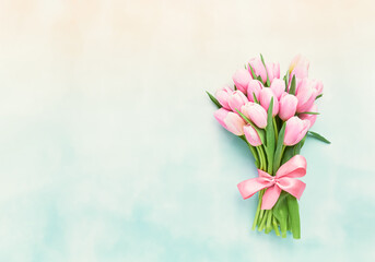 Pink tulips bouquet decorated with a pink bow on a pastel background. Mothers Day, Valentines Day, bachelorette concept.