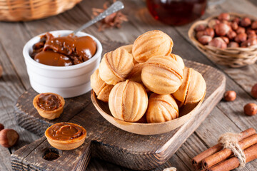 Fototapeta na wymiar Delicious walnut shaped cookies filled with sweet condensed milk and nuts on old wooden background