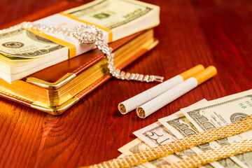 Money with a leather diary and cigarettes with jewellery on a mahogany table