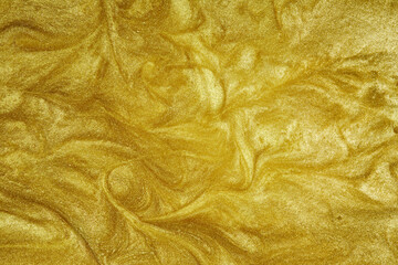 Golden liquid. The wavy surface of flowing gold. Abstract glittering background.