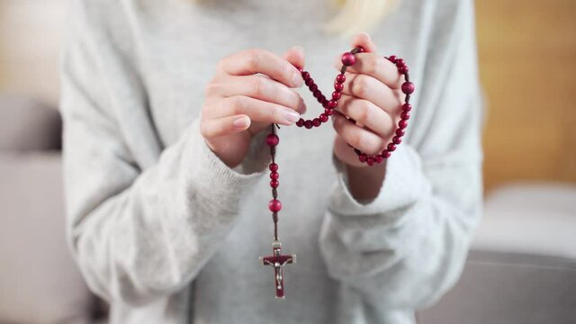 Christian rosary with close up Female. A woman's hands pray in a church or temple or at home. Prayer to the Virgin Mary and Jesus Christ. Closeup