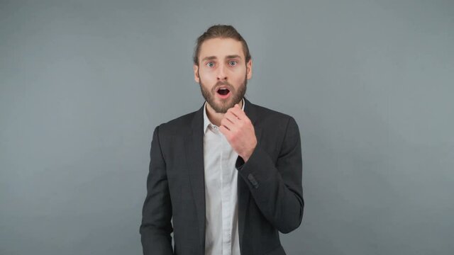 Surprised young business man in classic shirt tie posing isolated on gray background studio. Achievement career wealth business concept. Mock up copy space. Keeping mouth open, spreading hands
