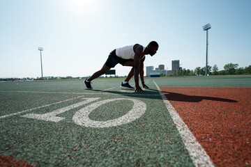 A male African American athlete prepares for a race at the stadium. At the start on the treadmill