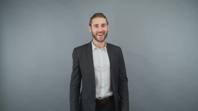 Young bearded man in a business suit approving nods and shows a gesture thumb up