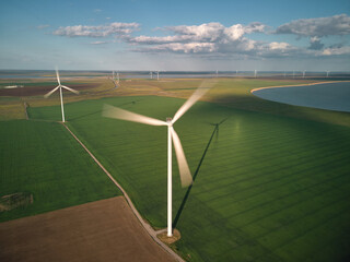 Aerial view of wind turbines and agriculture field near the sea at sunset