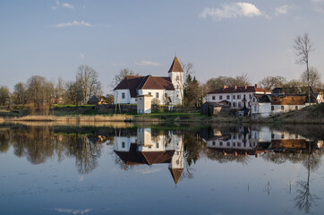 Fototapeta na wymiar Alsunga catholic church and reflection in lake, Latvia. 