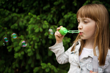 girl in a white denim jacket blowing soap bubbles