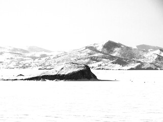 Snow-capped mountains by the lake. Black and white photography
