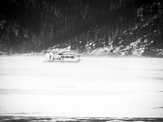 Hovercraft during a blizzard. Landscape with snow-covered trees. Black and white photography.