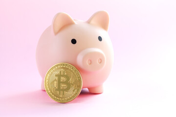 Pink piggy bank and bitcoin coin close-up