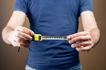 a man holds a centimeter in his hands and measures a penis