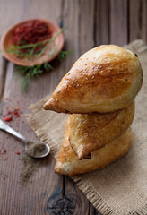 Delicious Samsa with lamb and spices cooked in tandoor on wooden background. Uzbek and Central Asia cuisine concept