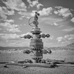 unused head of oil well with numerous valves in a desert landscape of central Utah, black and white...