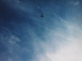 Airplane flying in the blue summer sky against the background of clouds