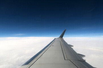 Fototapeta na wymiar Skrzydło samolotu pasażerskiego w locie na tle nieba i chmur.