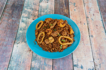 Oriental rice dish with seafood and vegetables on blue plate