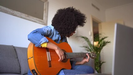 Positive black woman playing guitar at home