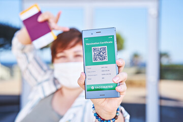 Happy woman holding smartphone displaying on app mobile valid digital green vaccination certificate for Covid-19. Immunity vaccine passport, vaccination certificate, health passport for travel