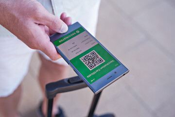 Smartphone in hand displaying on app mobile valid digital green vaccination certificate for Covid-19. Immunity vaccine passport, vaccination certificate, health passport for new normal travel