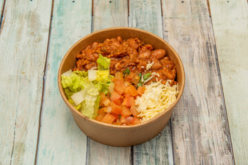 Photo at 45 degrees of Mexican chili con carne with cheese, diced tomatoes and lettuce