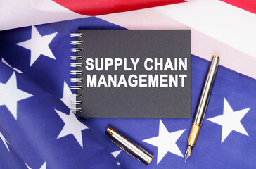 On the table is an American flag, a pen and a notebook with the inscription - SUPPLY CHAIN MANAGEMENT