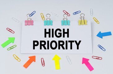 On the table there are paper clips and directional arrows, a sign that says - HIGH PRIORITY