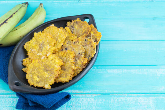 Fried plantain. Patacones on black plate on blue background. Copy space.