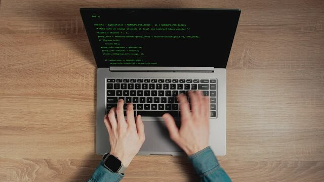Closeup a man hands are typing commands of a laptop keyboard. A man is writing a program. The developer is coding. Code on the laptop screen. Concept of programming and development web.