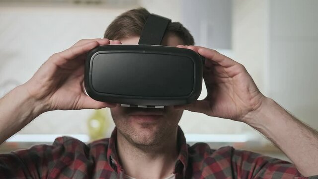 Man wearing VR headset at living room. Hi-tech device. Modern technologies. Virtual reality mask. 4K, UHD