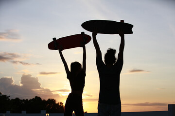 Outdoor sport concept, A couple man and woman lift surfskate board up over head