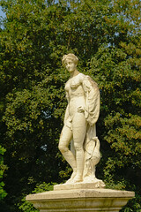 Fototapeta na wymiar Stone statue of a young noble man in the French formal gardens of the castle of Chantilly, Oise, France 