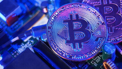 Bitcoin and semiconductor. Represent mining in Cryptocurrency cause global warming. Bitcoins on CPU board. Close-up Bitcoin with blue and pink light. circuit board with coin. Online asset concept. 
