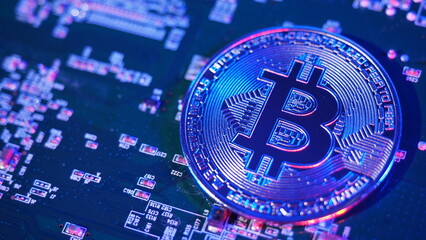 Bitcoin and semiconductor. Represent mining in Cryptocurrency cause global warming. Bitcoins on CPU board. Close-up Bitcoin with blue and pink light. circuit board with coin. Online asset concept. 